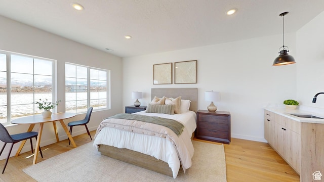 bedroom featuring a water view, sink, and light hardwood / wood-style floors