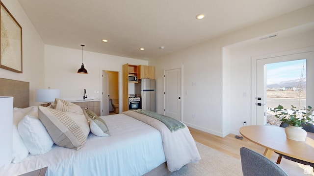 bedroom featuring light hardwood / wood-style floors, sink, and stainless steel refrigerator
