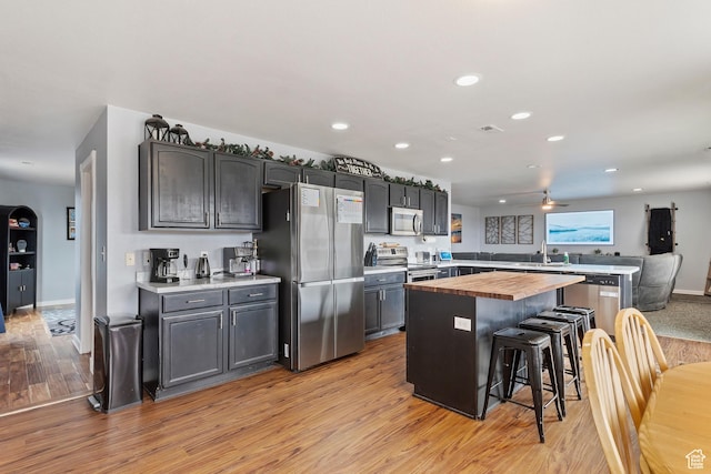 kitchen featuring a breakfast bar, butcher block countertops, recessed lighting, a ceiling fan, and stainless steel appliances