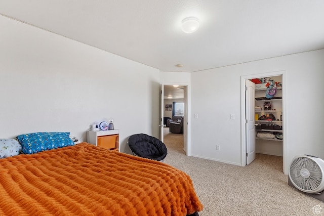 bedroom with a closet, baseboards, a walk in closet, and light carpet