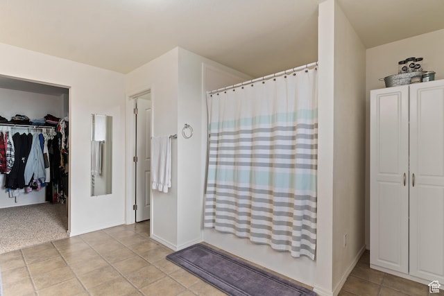 bathroom with baseboards, tile patterned flooring, and a walk in closet