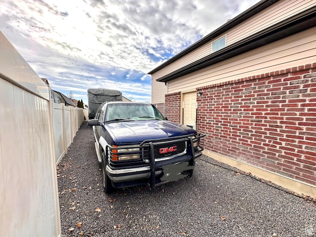 view of side of property with brick siding and fence