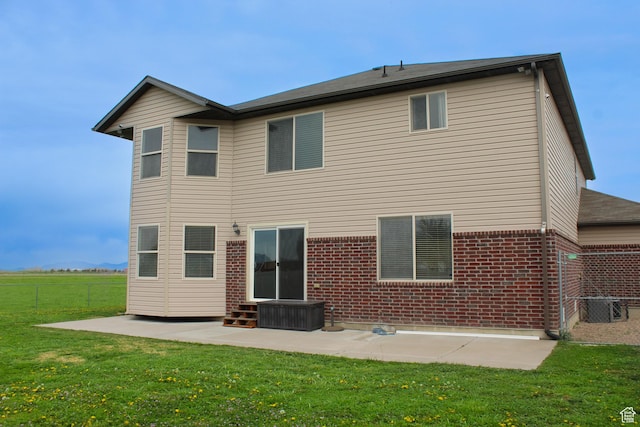 back of house with fence, brick siding, a patio area, central air condition unit, and a yard