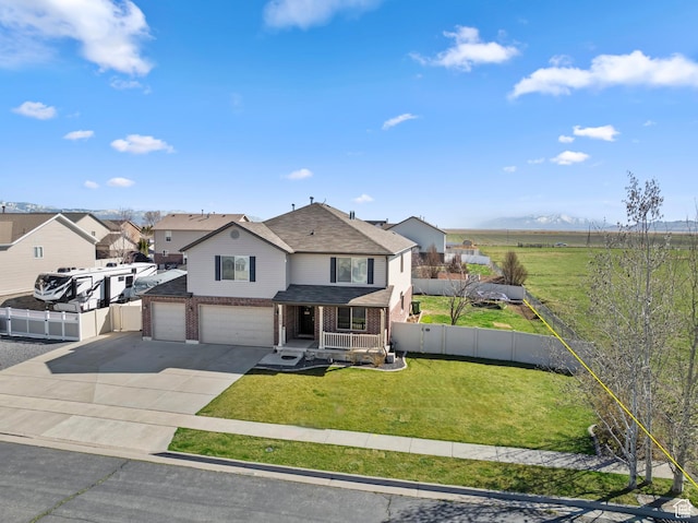 traditional-style home with fence, an attached garage, brick siding, a front yard, and driveway