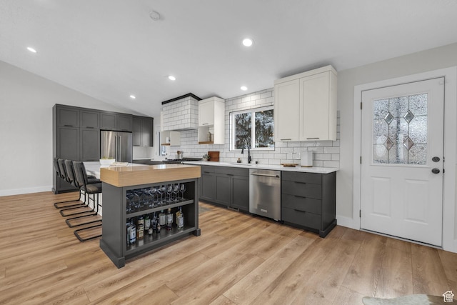 kitchen featuring stainless steel appliances, tasteful backsplash, a center island, and light wood-type flooring