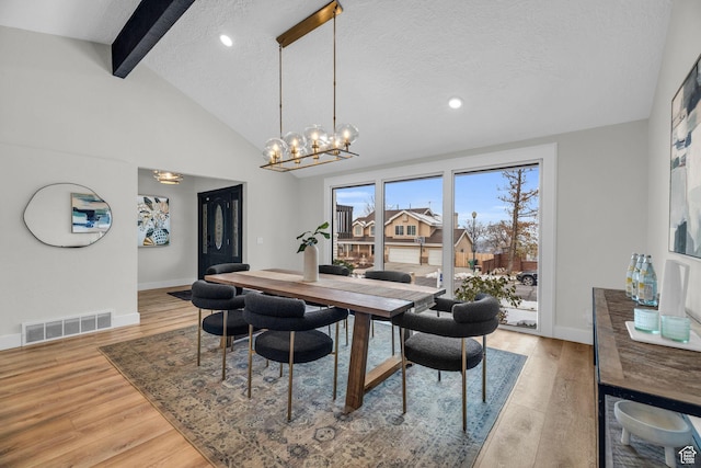 dining room with visible vents, light wood-type flooring, vaulted ceiling with beams, and a notable chandelier