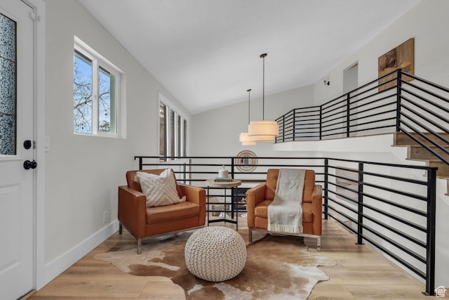 living area featuring wood finished floors, baseboards, vaulted ceiling, and an upstairs landing
