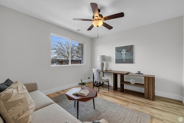living area with visible vents, baseboards, wood finished floors, and ceiling fan