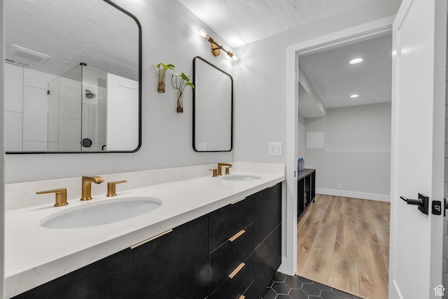 bathroom with a sink, a shower stall, double vanity, and wood finished floors