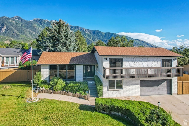 tri-level home featuring a garage, concrete driveway, fence, and a front lawn
