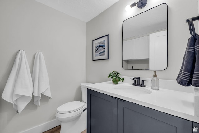 bathroom featuring vanity, baseboards, a textured ceiling, toilet, and wood finished floors