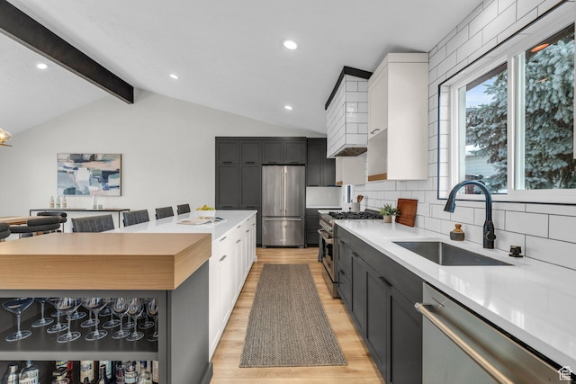 kitchen with light countertops, light wood-type flooring, a sink, and stainless steel appliances