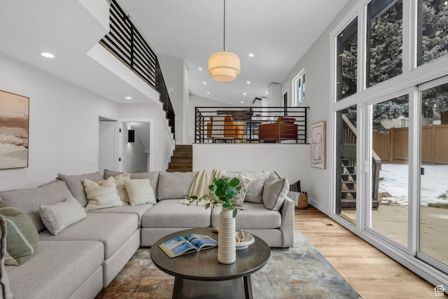 living area featuring recessed lighting, stairway, a high ceiling, and light wood finished floors