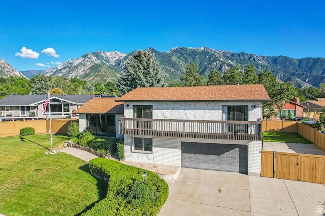 view of front of house featuring a front yard, fence, an attached garage, a mountain view, and concrete driveway