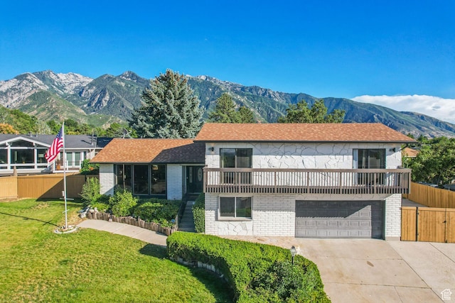 view of front facade featuring a mountain view, a garage, fence, a front lawn, and driveway