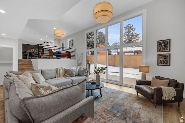 living room with high vaulted ceiling, recessed lighting, stairway, and wood finished floors