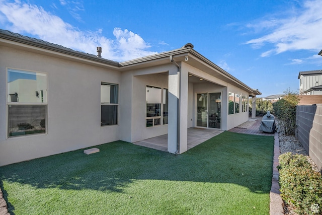back of property with a yard and a patio
