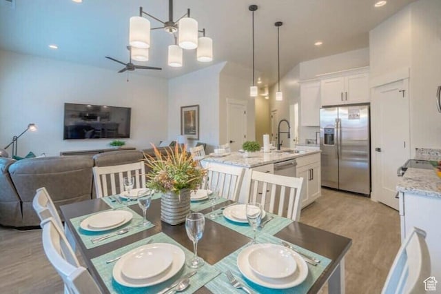 dining room with ceiling fan, sink, and light wood-type flooring