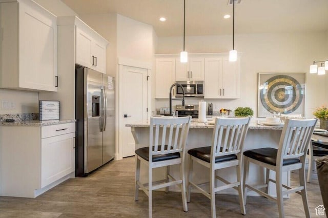 kitchen with light stone countertops, white cabinets, and stainless steel appliances