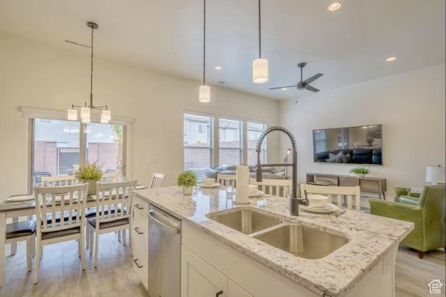 kitchen with an island with sink, decorative light fixtures, dishwasher, light stone countertops, and sink