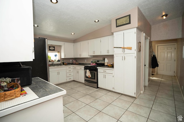 kitchen featuring appliances with stainless steel finishes, sink, vaulted ceiling, and white cabinets
