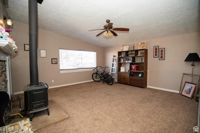 miscellaneous room with ceiling fan, carpet, a textured ceiling, vaulted ceiling, and a wood stove