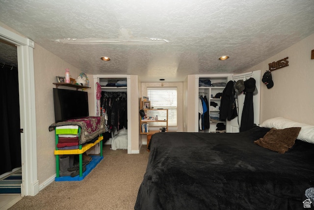 carpeted bedroom featuring multiple closets and a textured ceiling