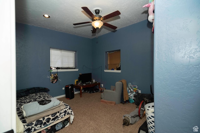 bedroom with ceiling fan, carpet flooring, and a textured ceiling