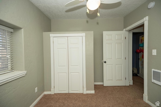 unfurnished bedroom with ceiling fan, carpet flooring, a closet, and a textured ceiling