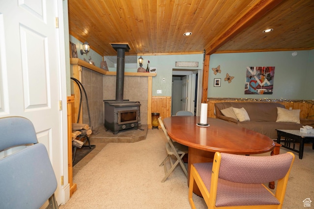 dining area with crown molding, a wood stove, wooden ceiling, light colored carpet, and wood walls