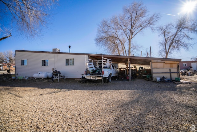 rear view of property featuring central AC and a carport