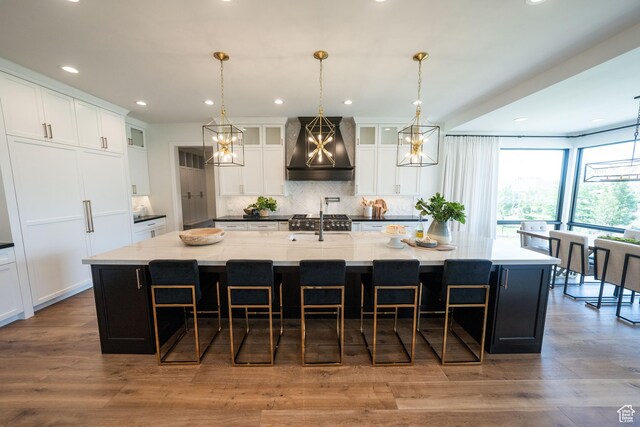 287 E Heritage Dr, Alpine, UT 84004 - kitchen featuring wall chimney exhaust hood, backsplash, a large island, a breakfast bar, and white cabinets