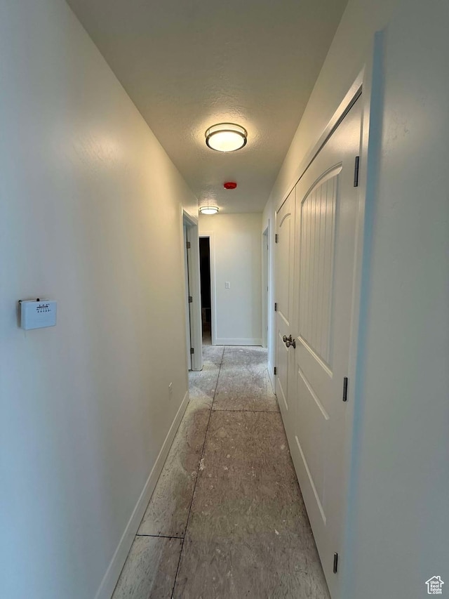 corridor featuring baseboards and a textured ceiling