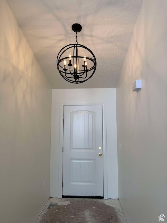 doorway to outside featuring unfinished concrete flooring and a notable chandelier