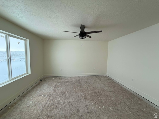 empty room featuring baseboards, ceiling fan, and a textured ceiling