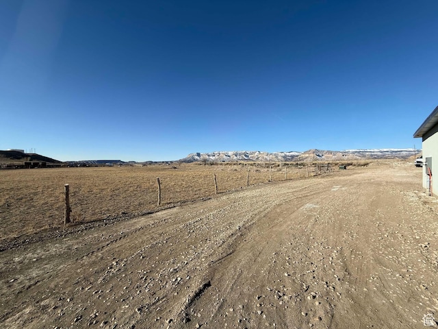 view of yard featuring fence, a rural view, and a mountain view