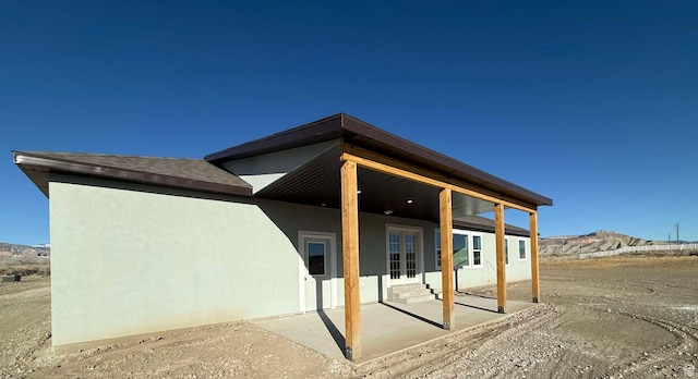 rear view of property featuring stucco siding, entry steps, a mountain view, and a patio