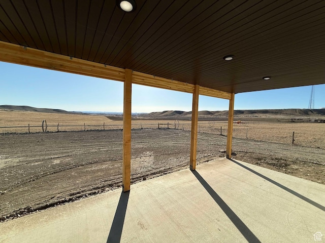 view of patio with a mountain view, fence, and a rural view