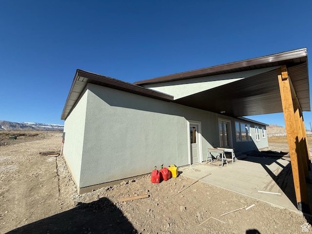 exterior space with stucco siding and a patio