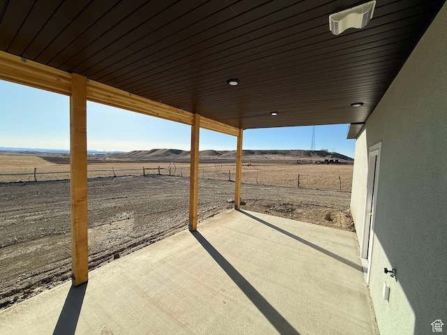 view of patio with a mountain view, fence, and a rural view