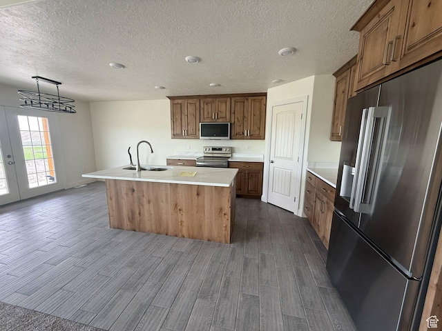1030 N 200 E, Ferron, UT 84523 - kitchen featuring appliances with stainless steel finishes, a sink, dark wood finished floors, a kitchen island with sink, and light countertops