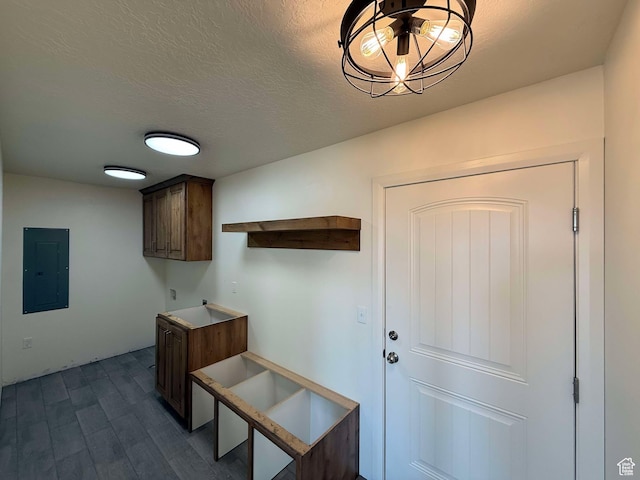 interior space with dark wood-type flooring, a textured ceiling, and electric panel