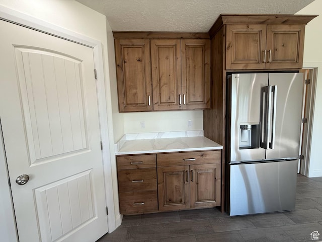 1030 N 200 E, Ferron, UT 84523 - kitchen featuring stainless steel fridge, brown cabinetry, a textured ceiling, and light stone countertops