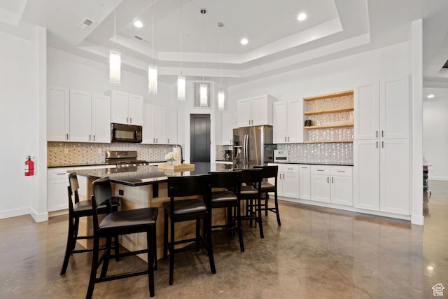 3243 S Hideaway Pl, Hurricane, UT 84737 - kitchen with a raised ceiling, a breakfast bar, appliances with stainless steel finishes, an island with sink, and white cabinets