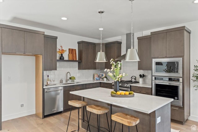6968 Elk Wallow Dr, Park City, UT 84098 - kitchen with light countertops, a kitchen bar, wall chimney exhaust hood, appliances with stainless steel finishes, and a sink