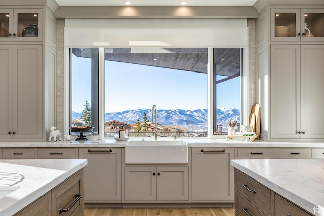 9491 N Promontory Summit Dr, Park City, UT 84098 - kitchen with light stone counters, glass insert cabinets, a sink, a mountain view, and light wood-type flooring