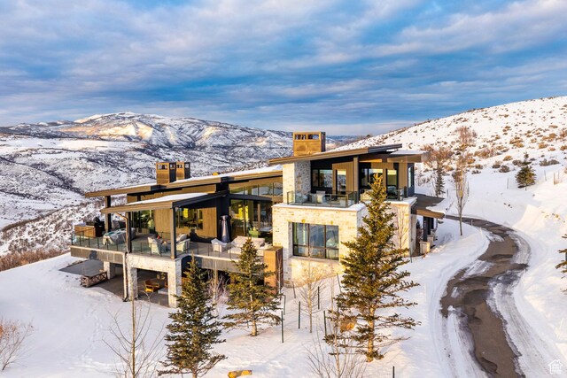 9491 N Promontory Summit Dr, Park City, UT 84098 - snow covered back of property with stone siding, a chimney, and a mountain view