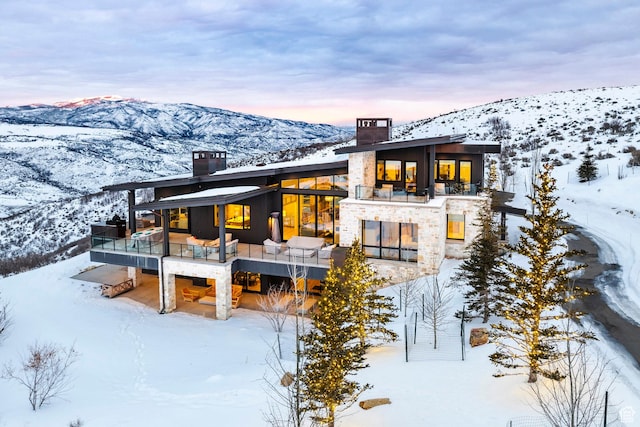 9491 N Promontory Summit Dr, Park City, UT 84098 - snow covered rear of property featuring stone siding, a mountain view, a chimney, and a balcony