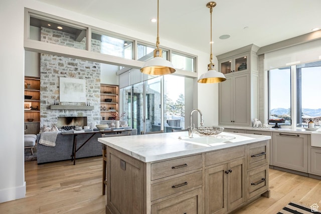 9491 N Promontory Summit Dr, Park City, UT 84098 - kitchen featuring a kitchen island with sink, decorative light fixtures, a sink, open floor plan, and glass insert cabinets