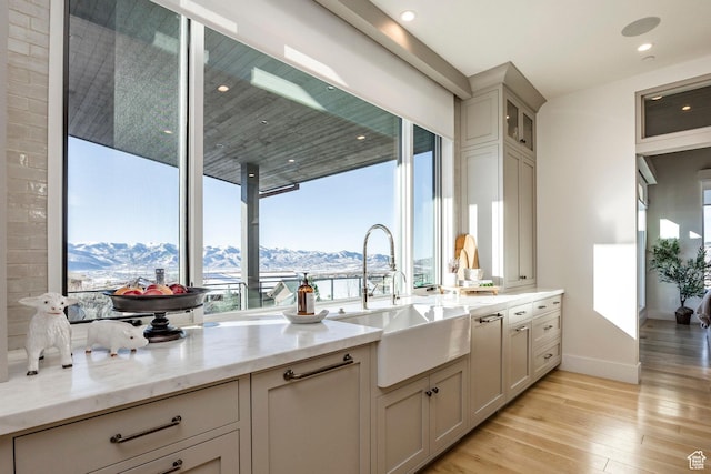 9491 N Promontory Summit Dr, Park City, UT 84098 - kitchen with a mountain view, a sink, light wood-style floors, light stone countertops, and glass insert cabinets